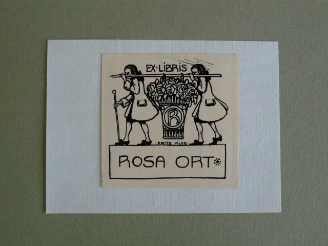 Klee, Fritz:  Exlibris für Rosa Ort. Motiv: Zwei Männer tragen mit einer Stange einen großen Korb voller Rosen, auf diesem prangt ein "R" 